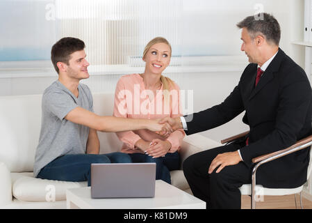 Reife männliche Berater die Hände schütteln, um Junge glückliches Paar Stockfoto