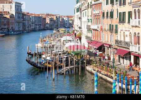 Blick von der Rialto Brücke bei Sonnenaufgang von Riva del Vin, Venedig, Venetien, Italien mit Restaurant Tabellen neben den Grand Canal und die Gondolieri worki Stockfoto