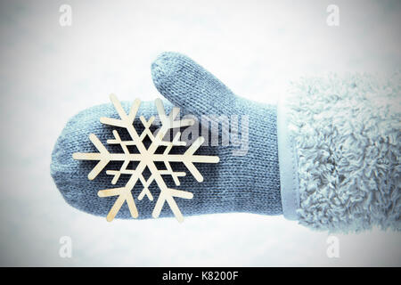 Wolle Handschuh mit Holz- Schneeflocke, Schnee Hintergrund Stockfoto