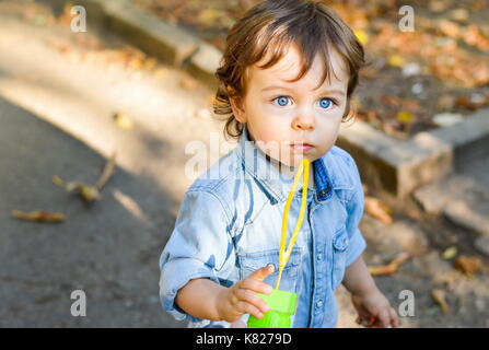 Blue eyed Boy im Park mit gefallenen Blätter im Herbst Stockfoto