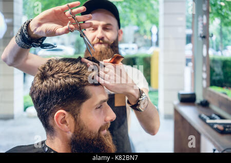 Dedizierte hairstylist mit Schere und Kamm, während eine Coo Stockfoto