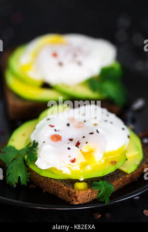 Roggen Toasts mit in Scheiben geschnittenen Avocado und pochierte Eier Stockfoto