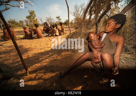 Ju/'Hoansi oder San Buschmänner Frau ein Baby in Gras Hütte auf einem Dorf, grashoek. Sie sind Mitglieder der verschiedenen indigenen Jäger-sammler Volk Namibia Stockfoto