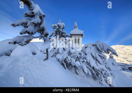 Der Glockenturm von Schnee umgeben von Wäldern Maloja Kanton Graubünden Engadin Schweiz Europa untergetaucht Stockfoto