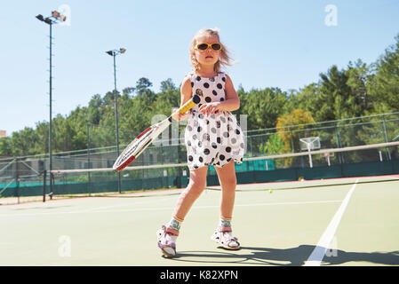 Süße kleine Mädchen spielen Sie Tennis auf dem Tennisplatz außerhalb Stockfoto