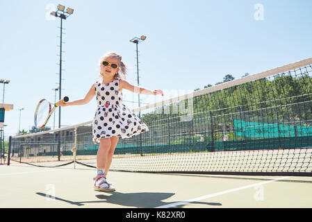 Süße kleine Mädchen spielen Sie Tennis auf dem Tennisplatz außerhalb Stockfoto