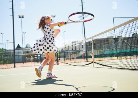 Süße kleine Mädchen spielen Sie Tennis auf dem Tennisplatz außerhalb Stockfoto