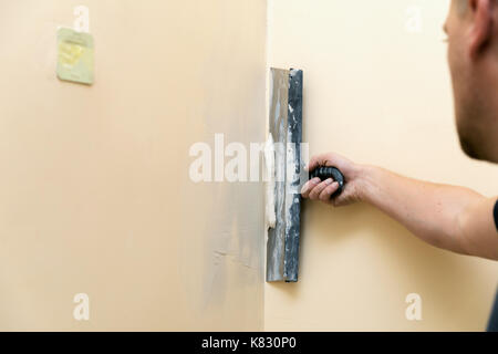 Arbeit richtet - Arbeitnehmer verputzen Wand mit Spachtel Stockfoto