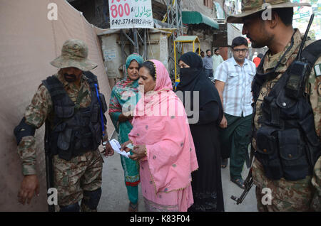 Lahore, Pakistan. 18 Sep, 2017. Sicherheit Personal stand guard Warteschlange als Wähler ihre Stimmzettel in NA zu werfen - 120 durch die Wahl. Wahl begann um 8 Uhr in 220 Wahllokalen in die Landeshauptstadt. Insgesamt 44 Kandidaten wetteifern für die Nationalversammlung Sitz von Lahore. Credit: Rana Sajid Hussain/Pacific Press/Alamy leben Nachrichten Stockfoto