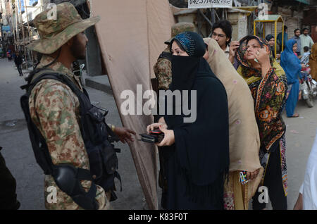 Lahore, Pakistan. 18 Sep, 2017. Sicherheit Personal stand guard Warteschlange als Wähler ihre Stimmzettel in NA zu werfen - 120 durch die Wahl. Wahl begann um 8 Uhr in 220 Wahllokalen in die Landeshauptstadt. Insgesamt 44 Kandidaten wetteifern für die Nationalversammlung Sitz von Lahore. Credit: Rana Sajid Hussain/Pacific Press/Alamy leben Nachrichten Stockfoto