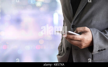 Person, die ein Smartphone auf unscharfen Stadtbild Hintergrund Stockfoto