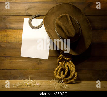 Cowboy Zubehör hängen an alten hölzernen Ranch Wand- und leeren weißen Hintergrund für Text Stockfoto