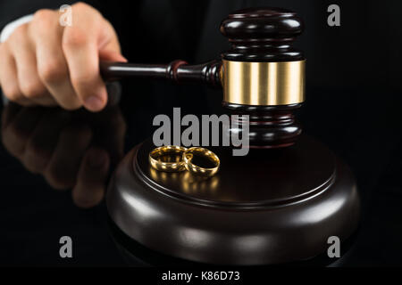 Close-up des Richters Hände schlagen Hammer mit goldenen Ringen auf Schreibtisch Stockfoto