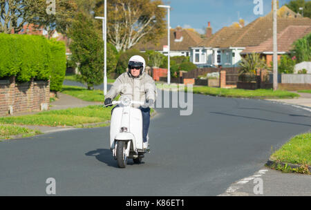 Lambretta Li 125 scooter in Weiß, in einer ruhigen Straße von einem Mann in Großbritannien geritten wird. Stockfoto