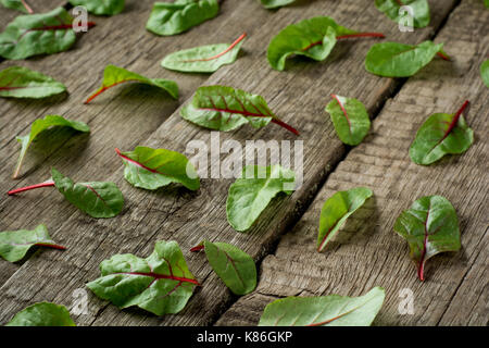 Salatblätter auf rustikalen Holzmöbeln Hintergrund. Flach grüne Salatblätter auf hölzernen Hintergrund Stockfoto