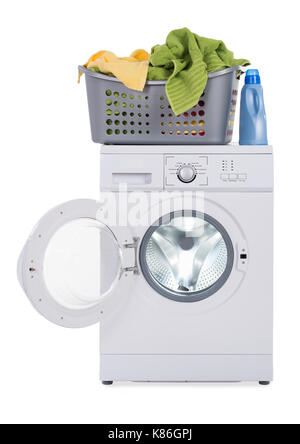 Wäschekorb voller schmutziger Kleidung auf Waschmaschine gegen den weißen Hintergrund Stockfoto