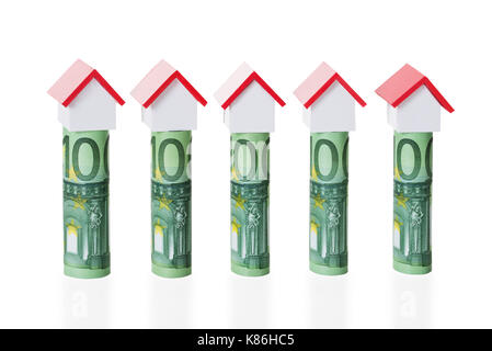 Haus Modelle auf gerollt Euro-Banknoten gegen weiße Hintergrund angeordnet Stockfoto