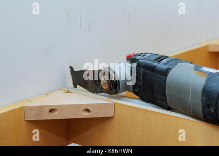 Oszillierende multi-function Power Tool auf Küchenschränke framing Hintergrund Stockfoto