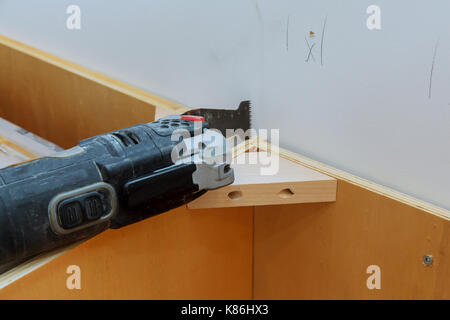 Oszillierende multi-function Power Tool auf Küchenschränke framing Hintergrund Stockfoto