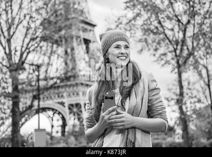 Herbst Kurzurlaube in Paris. lächelnde junge Touristen Frau in der Nähe von Eiffelturm mit Handy beiseite suchen Stockfoto