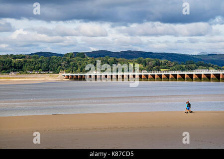 Zwei Menschen zu Fuß auf den Sand unten Arnside Viadukt als der Gezeiten liegender, Arnside, Cumbria, Großbritannien Stockfoto