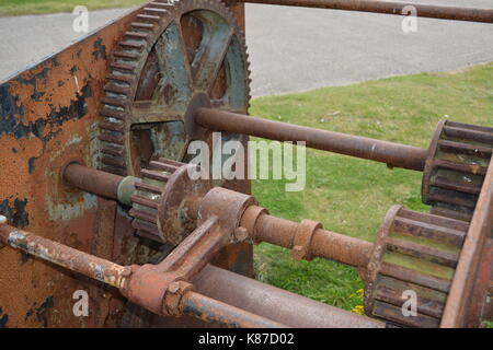 Nahaufnahme von alten verrosteten und abgenutzten Maschinen re industrielles Erbe Zahnräder und Räder auf grasbewachsenen Oberfläche in der Nähe von Nigg Scotland Cromarty Firth Stockfoto