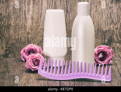 Haarpflege und Styling Kosmetik für Frauen. Haar Beauty Produkte und breiten Zahn Kamm mit Rosen auf Holz- Oberfläche. Getonten Bild mit Kopie Raum Stockfoto