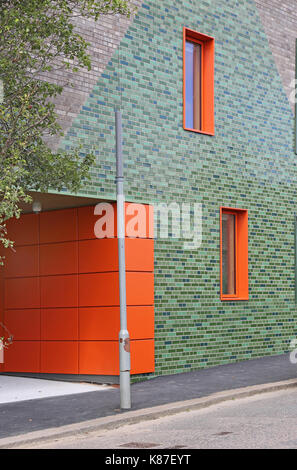 Fassade eines neuen primären Achool in Nunhead, London, UK, mit glasierten Ziegeln grün und orange Fassadenplatten und Fenster offenbart. Stockfoto