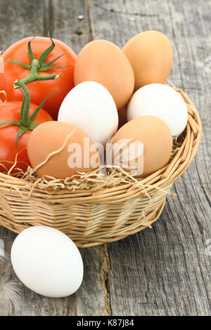 Frische Eier und Tomaten in den Korb Stockfoto
