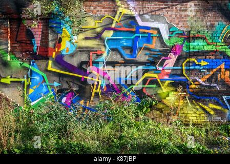 Futuristische bunte urban Graffiti inmitten wilder Pflanzen bewachsen. Stockfoto