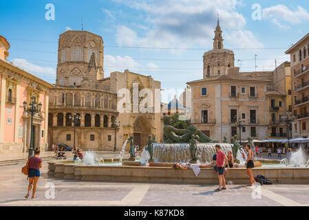 Valencia, Blick auf Touristen, die sich um den Brunnen auf der Plaza de la Virgen mit der Kathedrale und ihren zwei Türmen im Hintergrund entspannen, Valencia, Spanien Stockfoto