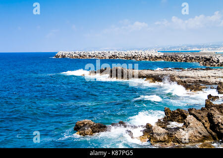 Wellen brechen an der felsigen Küste des Mittelmeers in der Nähe der venezianischen Festung (Fortezza) von Rethymno. Küste von Kolpos Almirou, Kreta, Griechenland Stockfoto