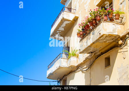 Schäbig, aber malerischen Balkon eines alten Gebäudes mit rosa Blumen in die Töpfe in der Altstadt von Rethymno, Kreta, Griechenland eingerichtet Stockfoto