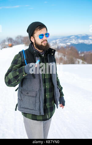 Bärtige Wanderer auf verschneiten Berg mit Wassertank Rucksack Stockfoto