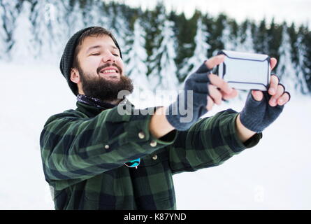 Bärtiger Mann unter selfie auf dem schneebedeckten Berg Stockfoto