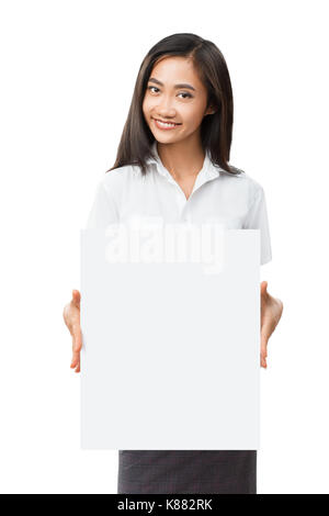 Junge lächelnde asiatische Frau mit leeren weißen Schild. Schöne Geschäftsfrau holding Banner mit Copyspace für Werbebotschaften, Plakate und tex Stockfoto