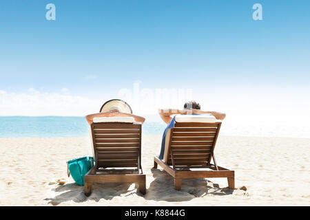 Junges Paar Liegen auf Liegestuhl am Strand Stockfoto