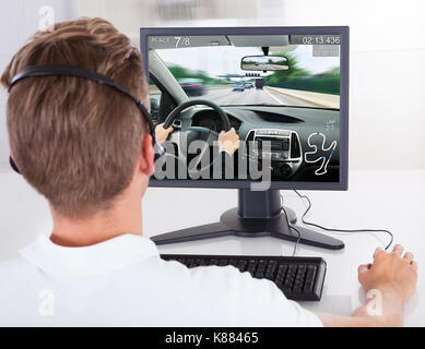 Ansicht der Rückseite des jungen Mannes spielen Auto Spiel auf dem Desktop Computer Stockfoto