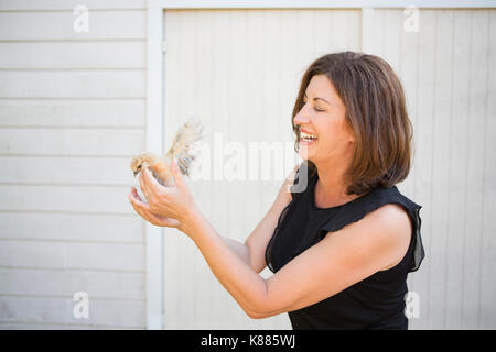 Eine Frau mit einem kleinen flauschigen Küken, ein Baby Bird in ihre beiden Hände. Stockfoto