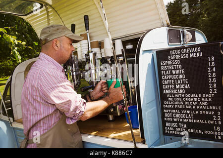 Der bärtige Mann mit Schürze ständigen von Blue mobile Coffeeshop, Kaffee machen. Stockfoto