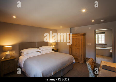 Ein gemütliches Schlafzimmer in neutralen Farben dekoriert, mit einem Doppelbett und Nachttischlampen auf. Gastfreundschaft. Stockfoto