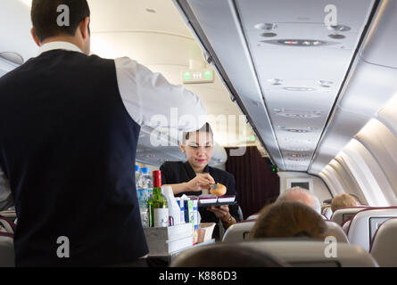 Qatar Airways - Cabin Crew, die an Bord; - die Stewardess das Essen auf einem A330-Flug Malediven zu Doha Stockfoto