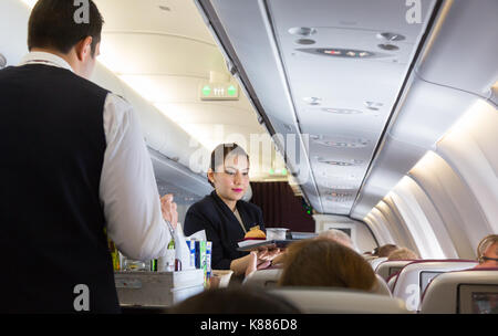 Cabin Crew arbeiten - eine Stewardess serviert Essen, Qatar Airways A330 Flug von Malediven zu Doha, Stockfoto