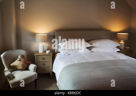 Ein gemütliches Schlafzimmer in neutralen Farben dekoriert, mit einem Doppelbett und Nachttischlampen auf. Gastfreundschaft. Stockfoto