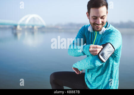 Sportler mit Phone, um Musik zu hören während der Ausführung und joggi Stockfoto