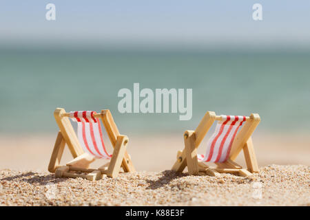 Foto von zwei Miniatur Liegestühle am Strand Stockfoto