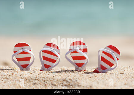 Zwei Paar gestreifte Flip-Flops am Strand Stockfoto