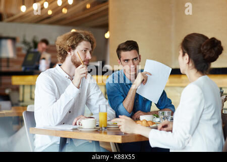 Nicht erkennbare junge Designer Ideen über die Start-up-Projekt mit ihrem stattlichen Kollegen während der Arbeit treffen auf modernes Cafe, blur Stockfoto