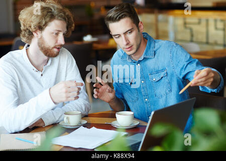 Gruppe junger Unternehmer zusammen im gemütlichen Café versammelt und die Vorbereitung auf die wichtigen Verhandlungen mit Geschäftspartnern, verschwommenen Hintergrund Stockfoto