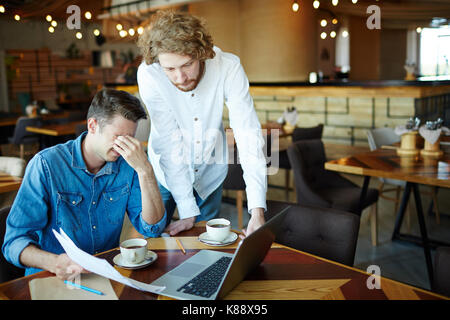 Müde Gruppe der Finanzmanager in casualwear Vorbereitung Jahresabschluss beim zusammen in der gemütlichen kleinen Café arbeiten Stockfoto